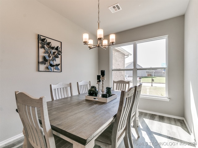 dining area with hardwood / wood-style floors and an inviting chandelier