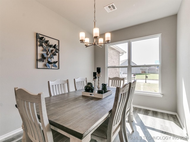 dining area with baseboards, wood finished floors, visible vents, and an inviting chandelier