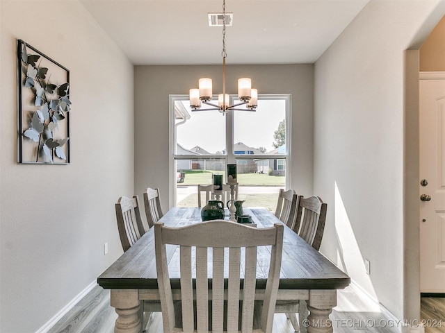 dining room featuring a chandelier, wood finished floors, visible vents, and baseboards