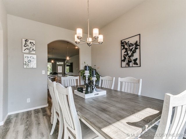 dining area with wood-type flooring and an inviting chandelier