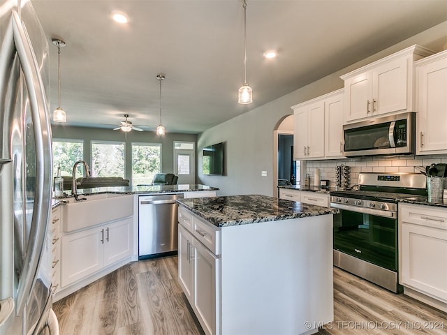 kitchen with white cabinetry, a kitchen island, stainless steel appliances, and decorative light fixtures