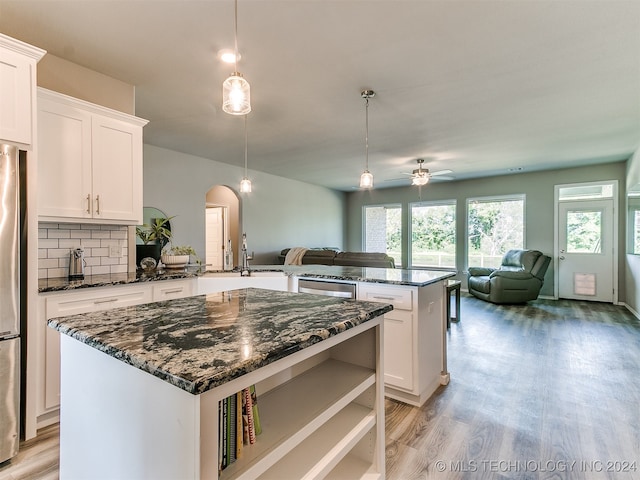 kitchen featuring light wood-type flooring, decorative light fixtures, kitchen peninsula, a center island, and ceiling fan