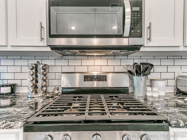 room details featuring appliances with stainless steel finishes, white cabinetry, and decorative backsplash