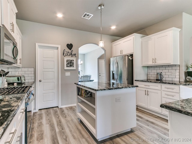 kitchen with stainless steel appliances, arched walkways, visible vents, and white cabinetry