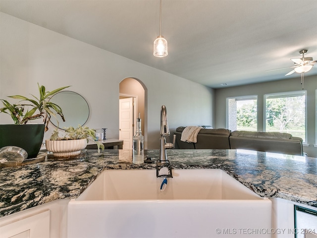 kitchen featuring ceiling fan, dark stone countertops, and sink