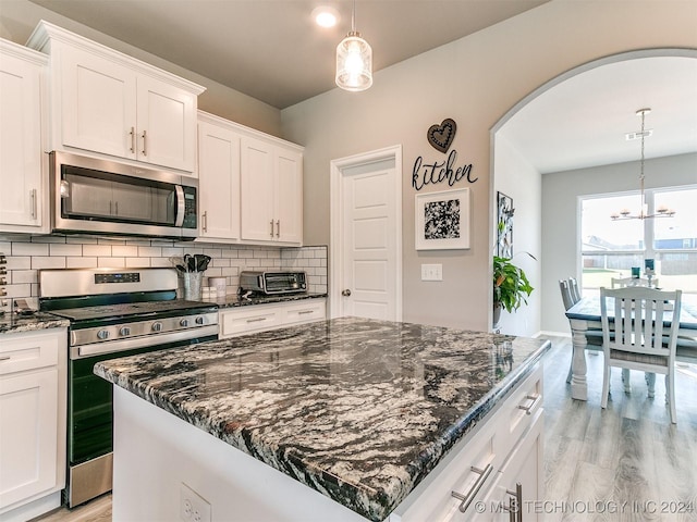 kitchen featuring stainless steel appliances, light wood finished floors, backsplash, and white cabinets