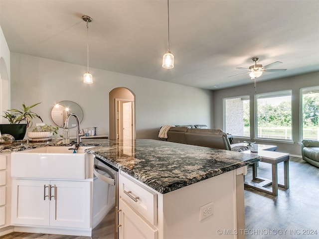 kitchen featuring arched walkways, a sink, white cabinets, open floor plan, and dishwasher