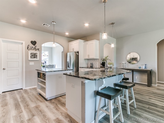 kitchen featuring light wood-type flooring, white cabinetry, decorative light fixtures, a kitchen island, and stainless steel fridge with ice dispenser