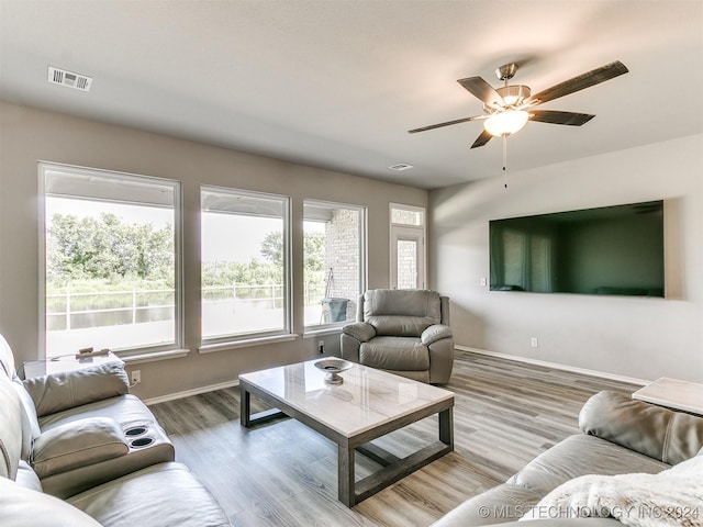 living area featuring baseboards, visible vents, and wood finished floors