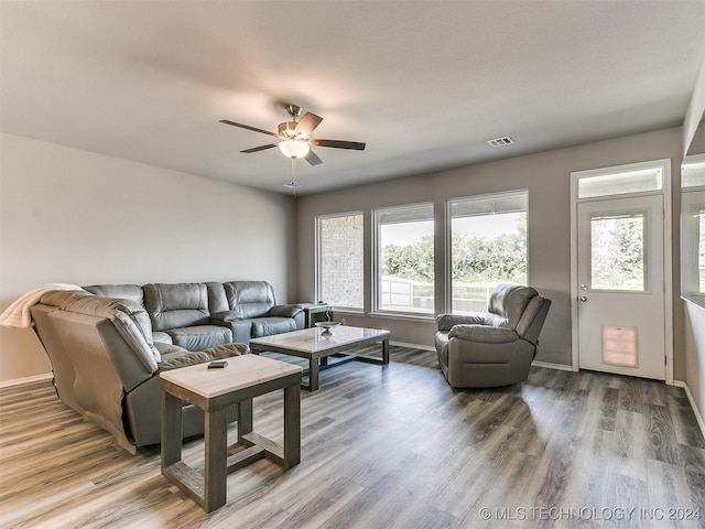 living room featuring ceiling fan, visible vents, baseboards, and wood finished floors