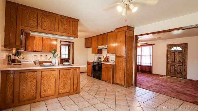 kitchen with kitchen peninsula, sink, black / electric stove, light colored carpet, and ceiling fan