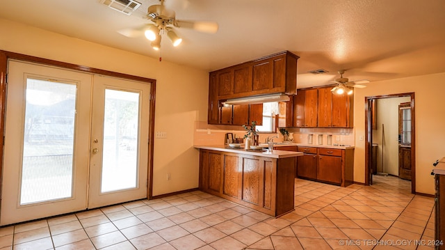 kitchen with plenty of natural light, french doors, light tile patterned floors, and kitchen peninsula