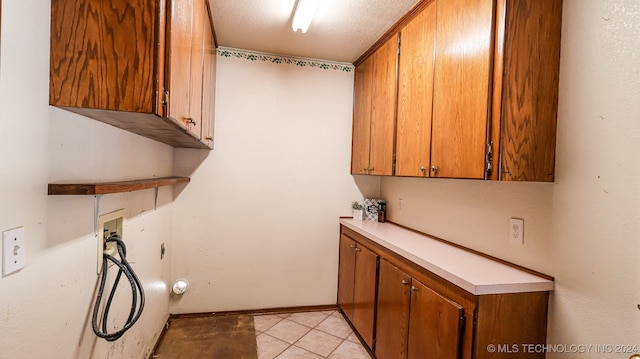 laundry room featuring hookup for a washing machine, a textured ceiling, light tile patterned floors, and cabinets