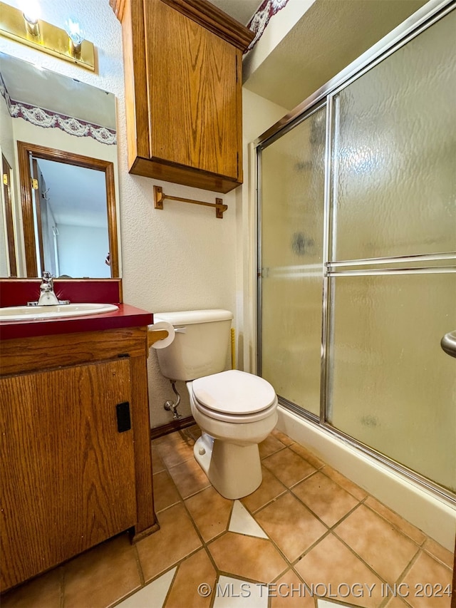 bathroom featuring vanity, toilet, tile patterned floors, and a shower with door