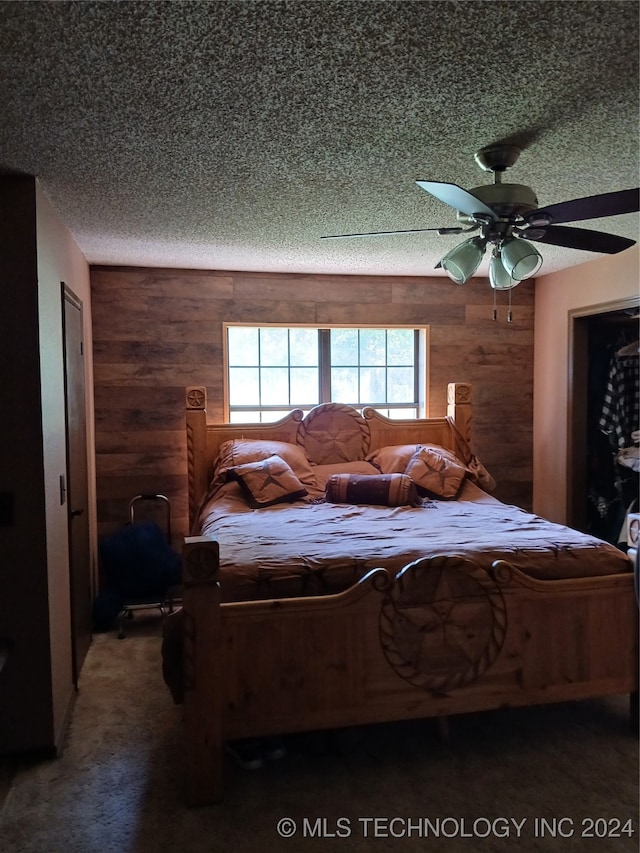 carpeted bedroom with a textured ceiling, wood walls, and ceiling fan