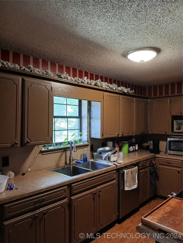 kitchen featuring wood-type flooring, stainless steel appliances, sink, and a textured ceiling