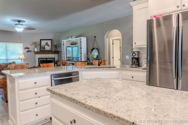 kitchen with sink, light stone countertops, white cabinets, and appliances with stainless steel finishes