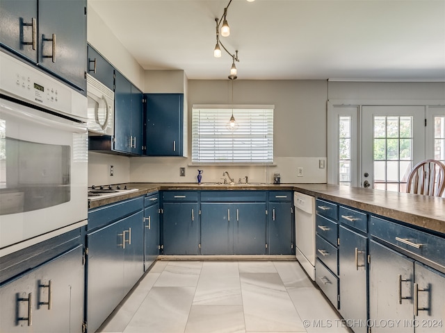 kitchen featuring blue cabinetry, white appliances, decorative light fixtures, and sink