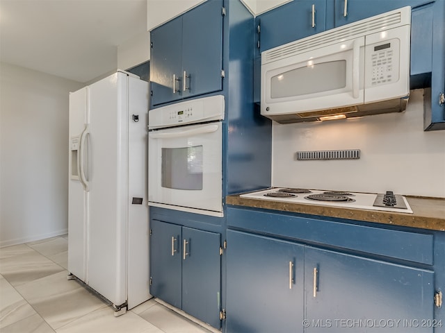 kitchen featuring light tile patterned flooring, white appliances, and blue cabinetry