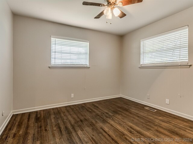 empty room with dark hardwood / wood-style floors, a healthy amount of sunlight, and ceiling fan