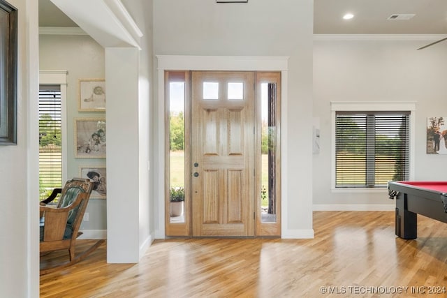 foyer entrance with billiards, plenty of natural light, crown molding, and light hardwood / wood-style flooring