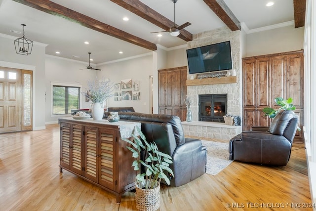 living room featuring ceiling fan, light hardwood / wood-style floors, crown molding, and a stone fireplace