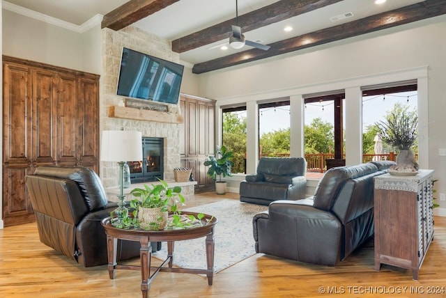 living room with ceiling fan, a fireplace, beamed ceiling, and light hardwood / wood-style flooring