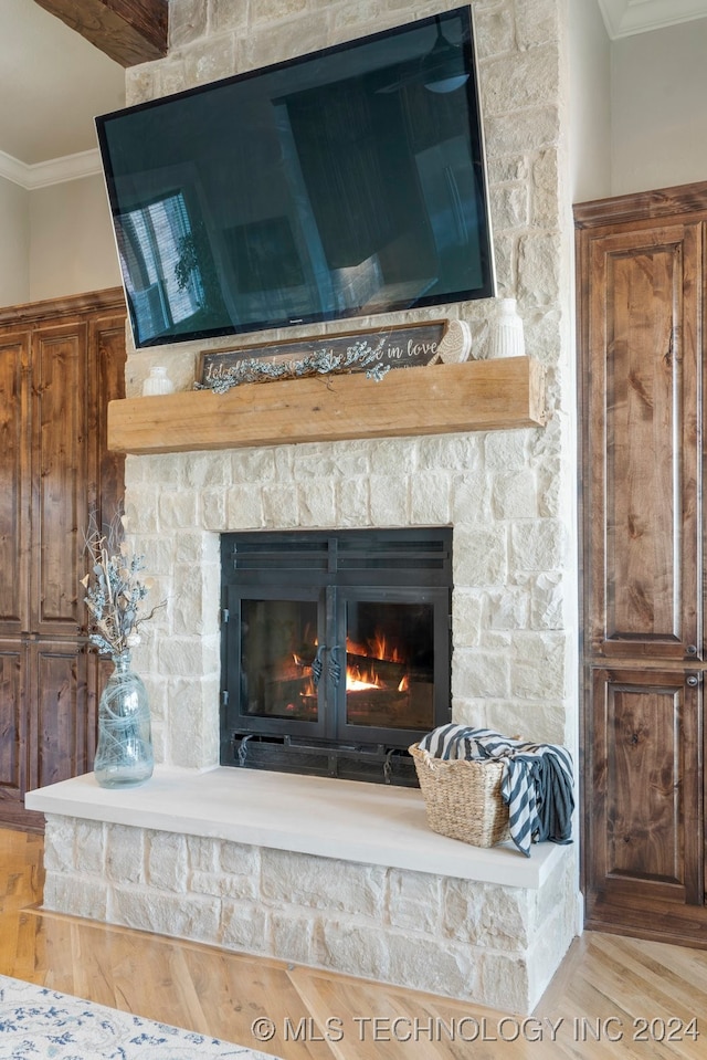 room details with hardwood / wood-style flooring, crown molding, and a stone fireplace