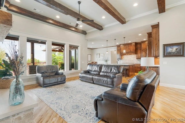 living room with ceiling fan, light hardwood / wood-style floors, and beamed ceiling