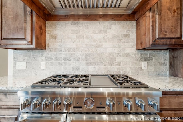 kitchen with decorative backsplash, light stone counters, custom exhaust hood, and stainless steel range oven