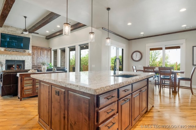 kitchen with light hardwood / wood-style flooring, ceiling fan, sink, and a stone fireplace