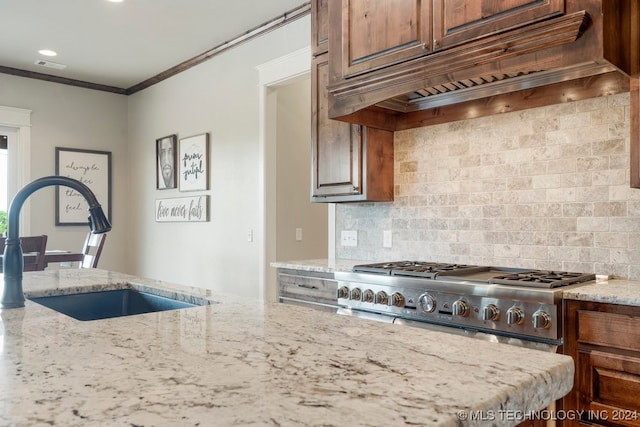 kitchen with light stone countertops, premium range hood, ornamental molding, sink, and decorative backsplash