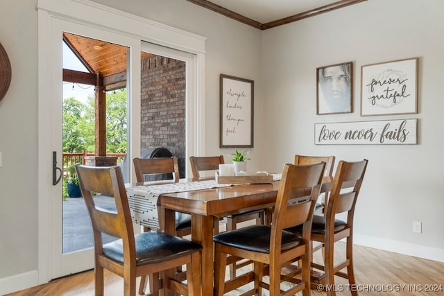 dining space featuring crown molding, light wood-type flooring, and a fireplace