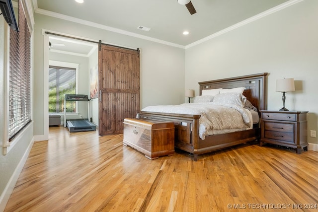 bedroom with ceiling fan, a barn door, and light hardwood / wood-style floors