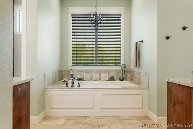 bathroom featuring vanity, a chandelier, a wealth of natural light, and a tub