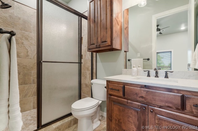 bathroom featuring a shower with shower door, vanity, toilet, tile patterned floors, and ceiling fan