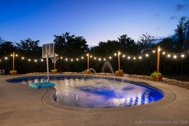 pool at dusk featuring pool water feature