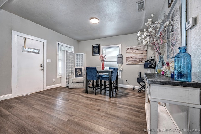 dining area with a textured ceiling and dark wood-type flooring