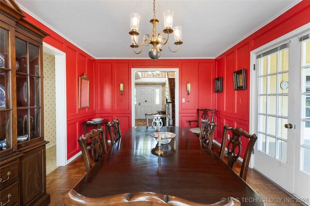 dining area featuring ornamental molding, dark parquet flooring, and a chandelier