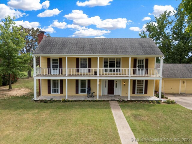 view of front facade with a front yard, a balcony, a garage, and covered porch