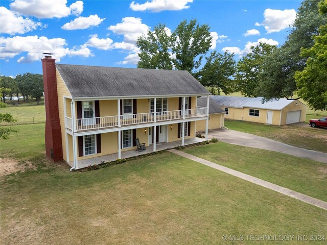 view of front of property featuring a porch, a balcony, an outbuilding, a front yard, and a garage