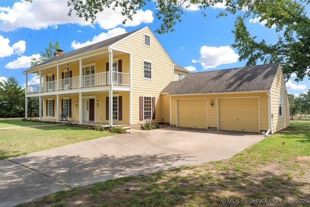 view of front of home with a balcony, a front yard, a porch, and a garage