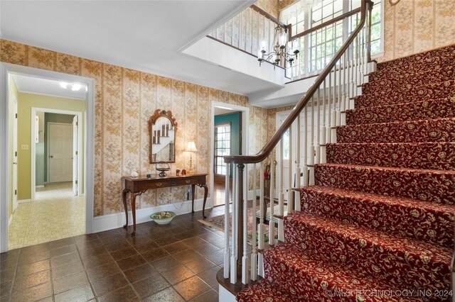 stairs with an inviting chandelier and crown molding