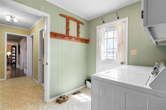 laundry room with ornamental molding, wood walls, and washer and dryer