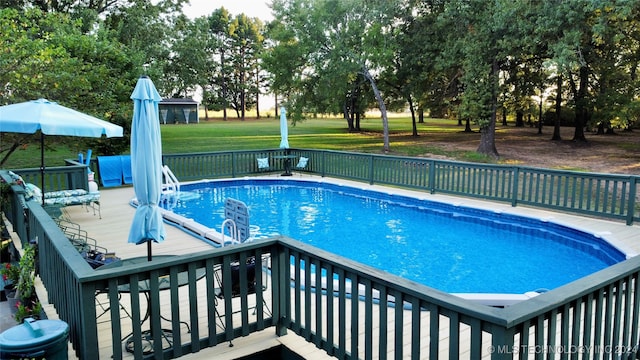 view of pool with a wooden deck and a yard