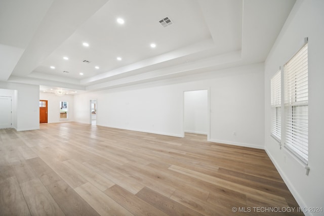 unfurnished living room featuring light wood-type flooring and a raised ceiling