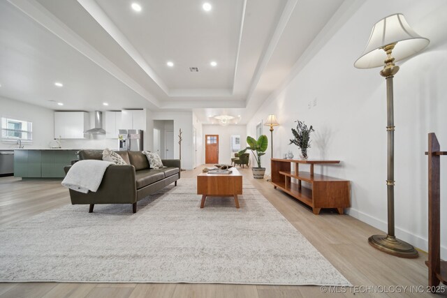 kitchen with stainless steel appliances, wall chimney range hood, white cabinetry, a kitchen island, and green cabinets