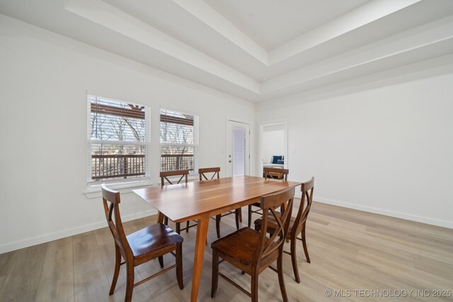 unfurnished room with light wood-type flooring and a raised ceiling