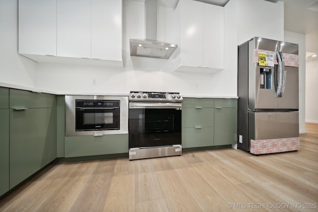 kitchen featuring green cabinetry, ventilation hood, light hardwood / wood-style flooring, stainless steel appliances, and white cabinets