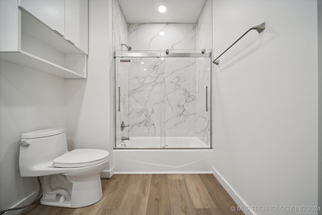 bathroom with shower / bath combination with glass door, toilet, and wood-type flooring